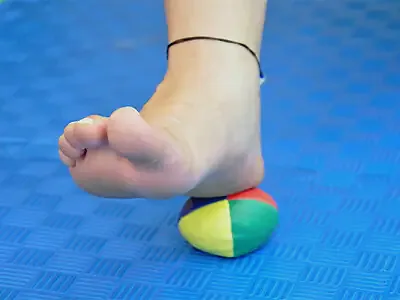 The foot rolls a colourful ball under its toes